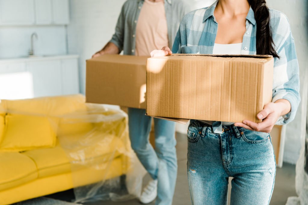 husband and wife carrying cardboard boxes and packing for new house, moving concept